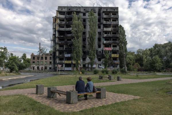 A couple sits in front of a residential building that was damaged during a Russian attack, in Borodyanka. EPA