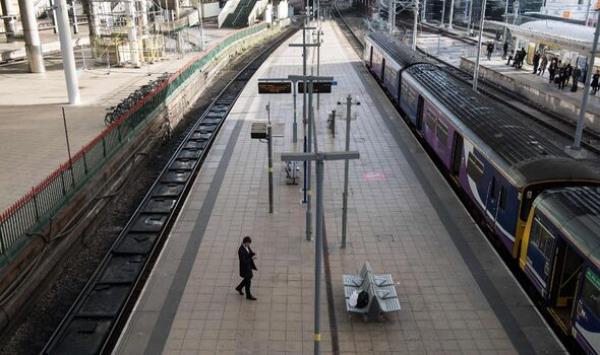 A man waits on a platform in Manchester Victoria train station during a reduced transport service due to industrial action