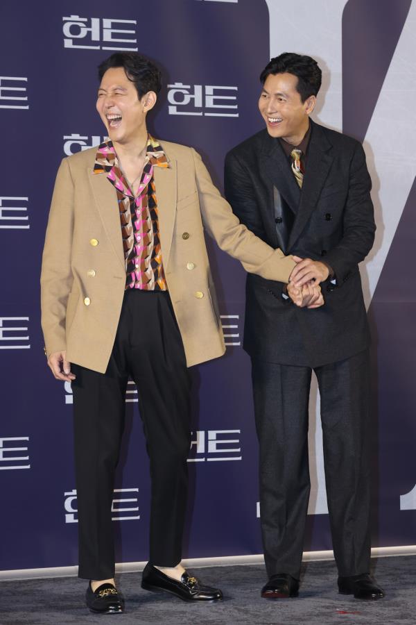 Lee Jung-jae (left) and Jung Woo-sung hold hands during a photo session after a press co<em></em>nference introducing “Hunt” at Megabox Seo<em></em>ngsu in Seoul, Tuesday. (Yonhap)
