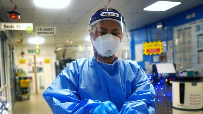 A nurse puts on gloves in a Lo<em></em>ndon hospital
