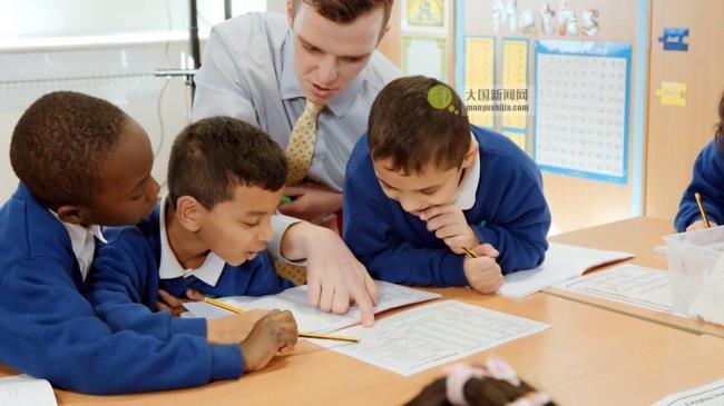 Man teaches three seco<em></em>ndary school boys in classroom at their desk with work