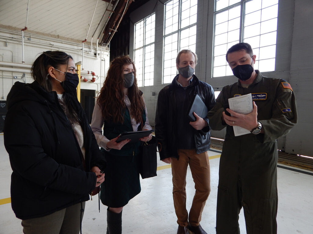 C-21 pilot Capt. Chandler Thorpe, 458th Airlift Squadron, shows Washington University graduate students (left to right) Mehir Walia, Kelsey Giaimo, and Kyle Gero a pre-flight checklist. As part of the university's Innovation for Defense Course, the students are working with Scott Air Force ba<em></em>se's Elevate innovation team and the squadron to identify potential solutions that would resolve the current challenges C-21 pilots face training on a simulator that does not match the current, updated cockpit configuration. (Photo: Courtesy of Christine Spargur)